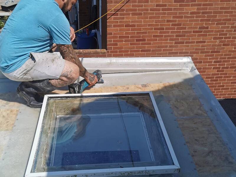 Roofer installing flat roof and skylight